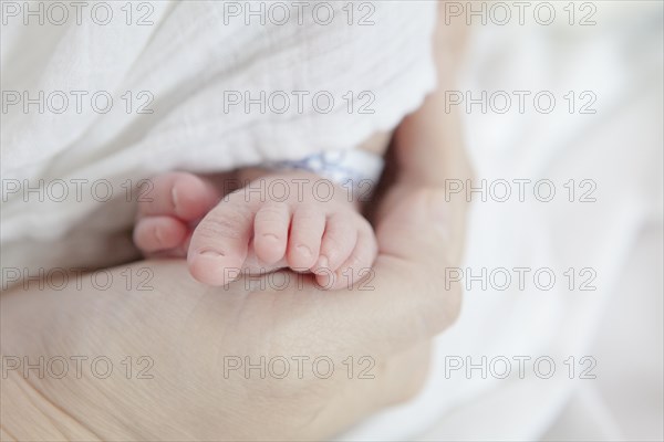 Caucasian mother holding foot of newborn daughter