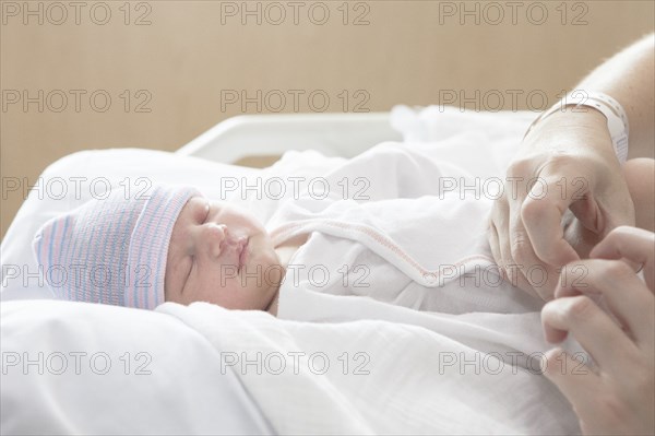 Caucasian mother holding newborn daughter in hospital bed