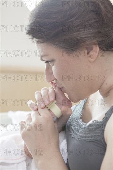 Caucasian mother kissing foot of newborn daughter