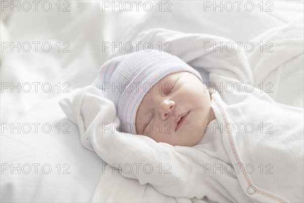 Caucasian newborn girl laying on bed