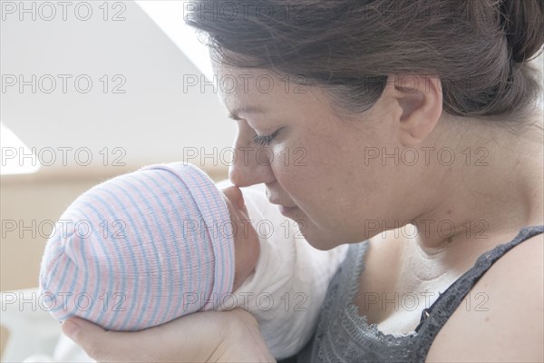 Caucasian mother rubbing noses with newborn daughter