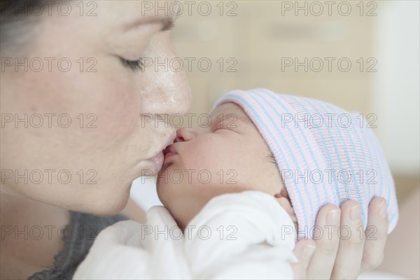 Caucasian mother kissing newborn daughter