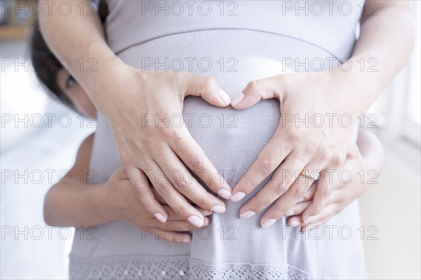 Hispanic girl holding belly of pregnant mother