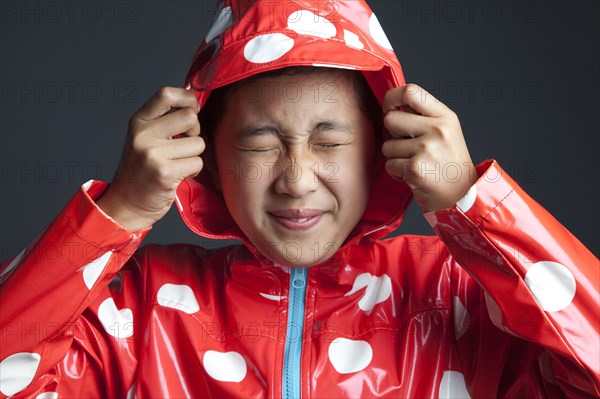 Smiling Asian girl wearing hooded raincoat