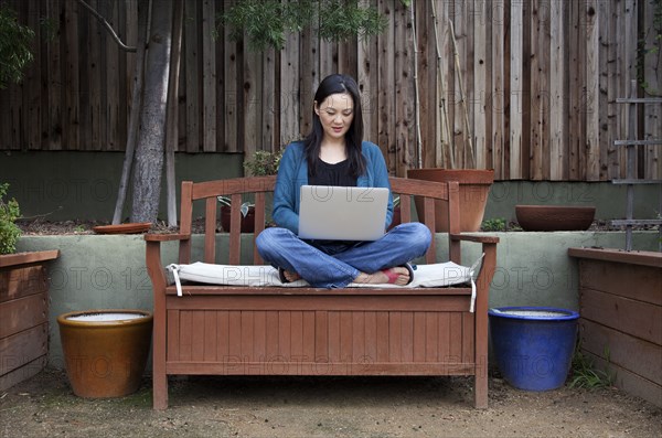 Korean woman using laptop in backyard