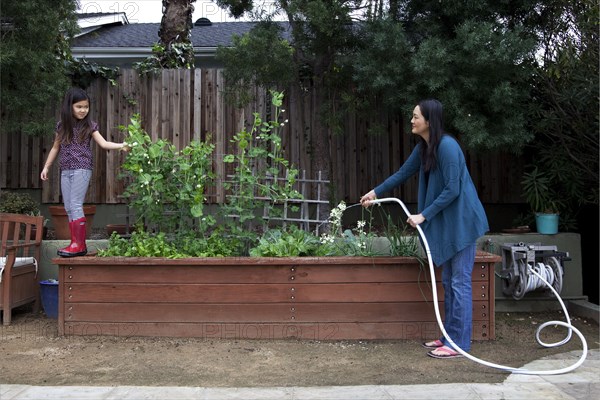 Mother and daughter gardening in backyard