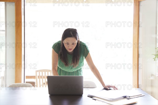 Korean woman using laptop in dining room