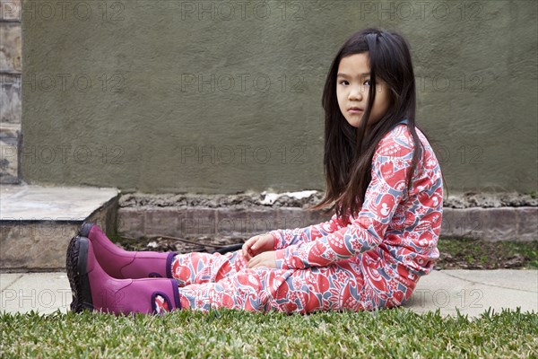 Angry mixed race girl sitting in backyard