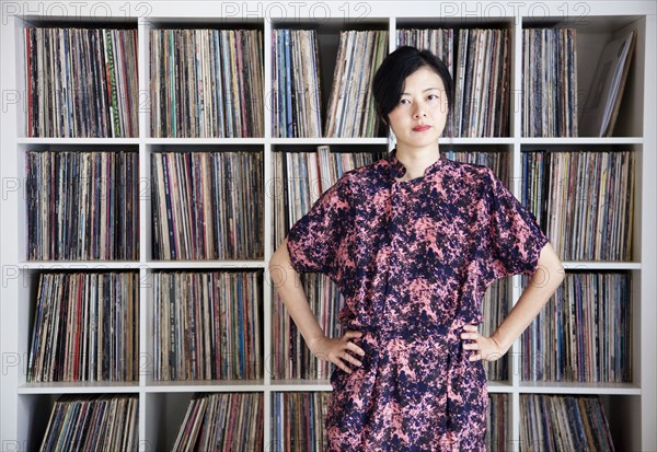 Taiwanese woman standing near record collection