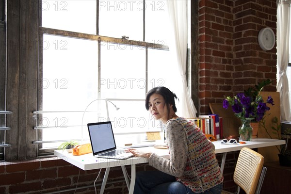 Taiwanese woman using laptop in home office