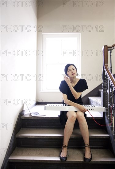 Taiwanese woman playing keyboard on staircase