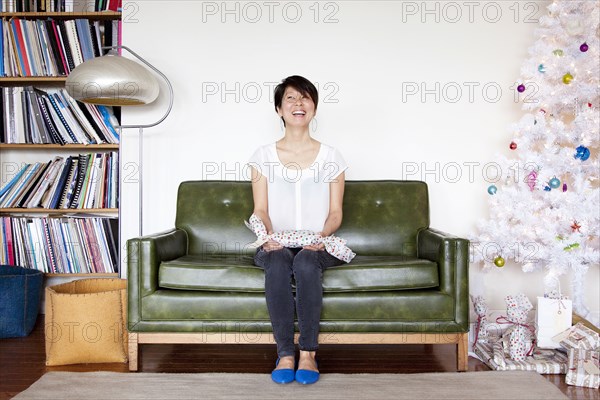 Japanese woman holding gift near Christmas tree