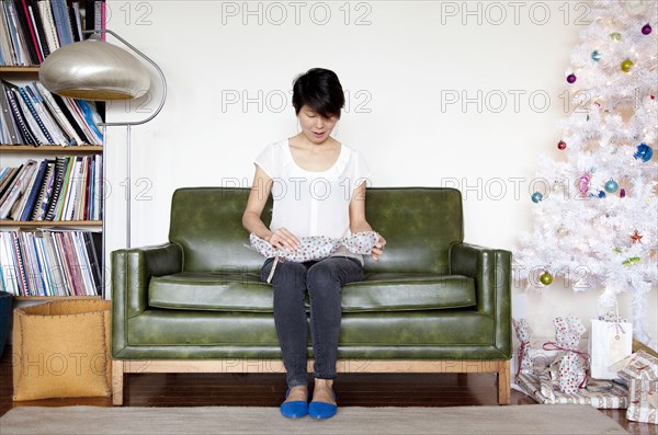 Japanese woman opening gift near Christmas tree