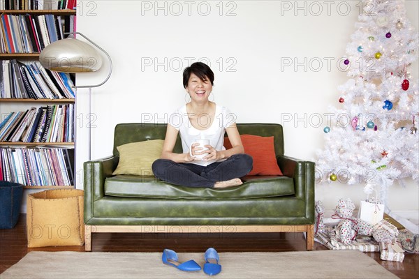 Japanese woman drinking coffee near Christmas tree