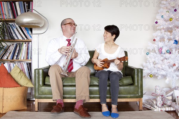 Couple playing music near Christmas tree