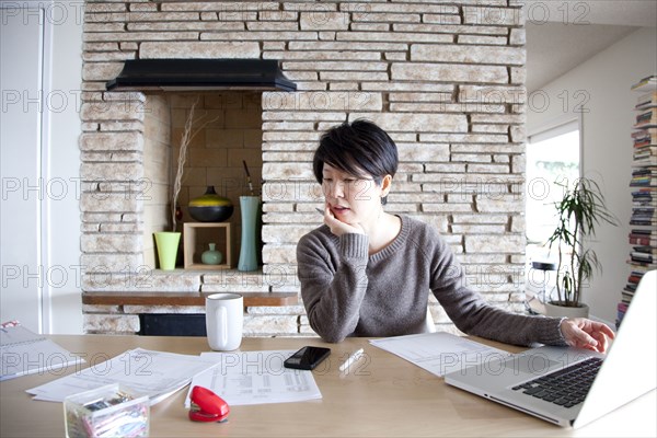 Japanese woman paying bills on laptop