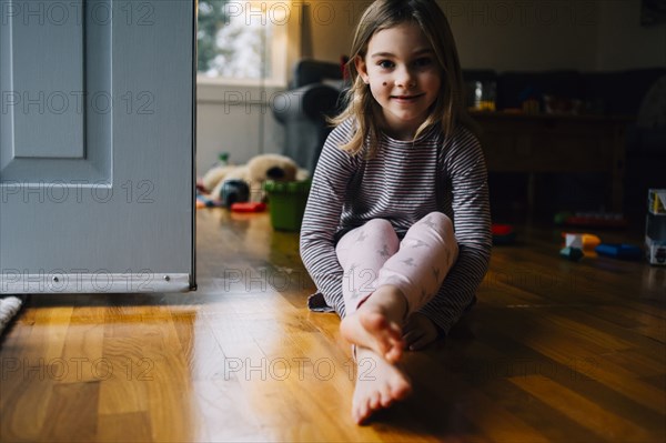 Smiling girl sitting on playroom floor