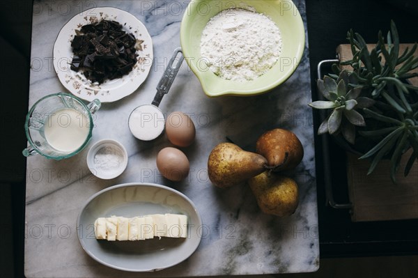 Close up of baking ingredients and pears on marble counter