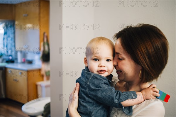 Smiling mother nuzzling son in kitchen