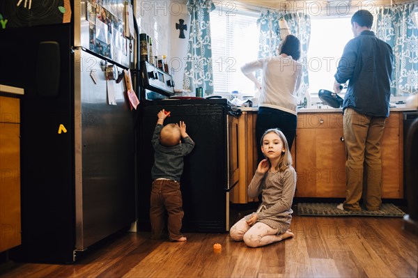 Children playing as parents cook in kitchen