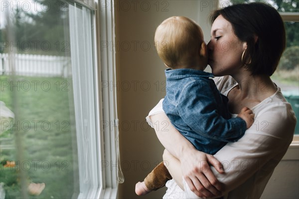 Mother kissing son at window