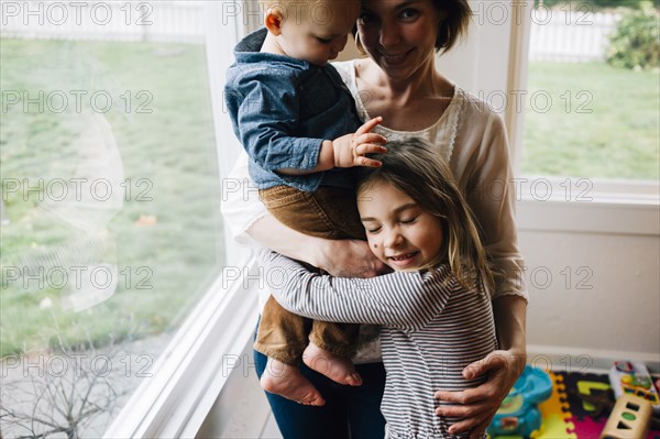 Mother and children hugging at window