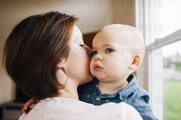 Mother kissing son at window