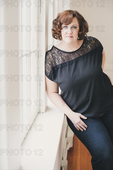 Smiling woman leaning on windowsill