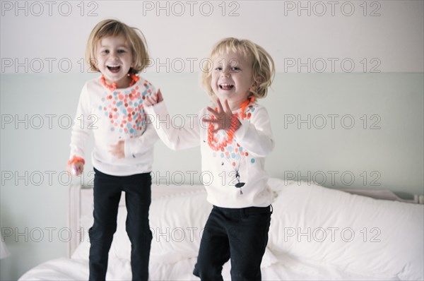 Playful sisters jumping on bed