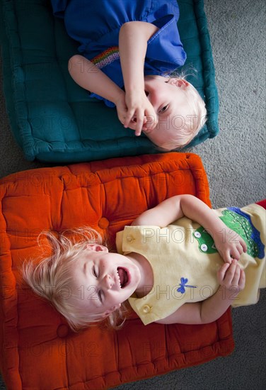 Brother and sister playing on cushions on floor