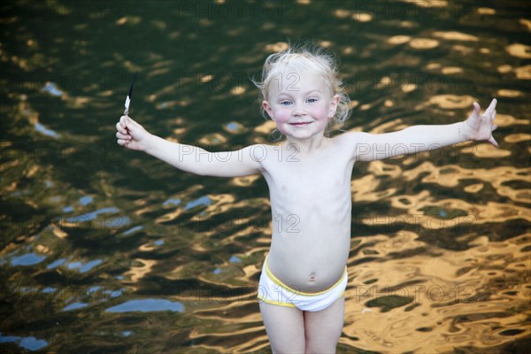 Smiling girl standing with arms outstretched at lake
