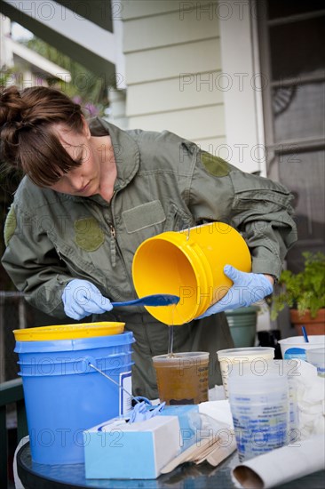 Woman pouring liquid in backyard