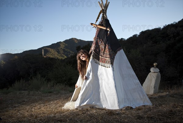 Hispanic woman smiling in teepee in field