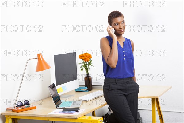 Black businesswoman talking on cell phone at office desk