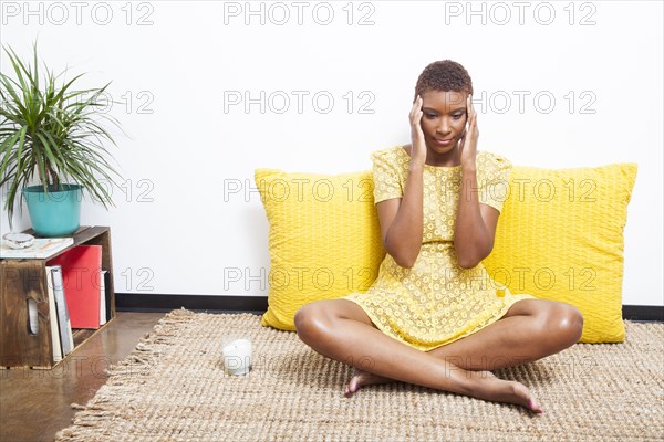 Stressed Black woman meditating on floor