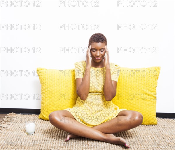 Stressed Black woman meditating on floor