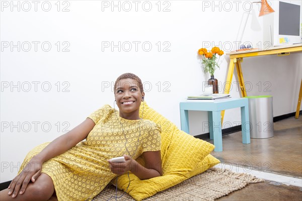 Black woman listening to mp3 player on floor