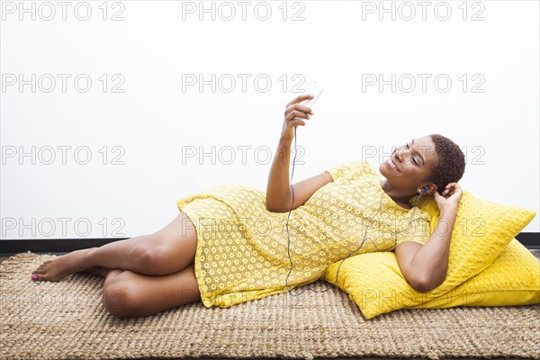 Black woman listening to mp3 player on carpet