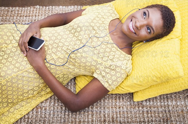 Black woman listening to mp3 player on carpet