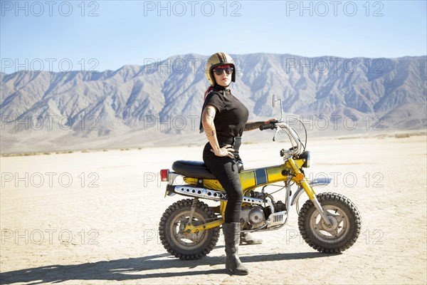 Woman standing on motorcycle in desert