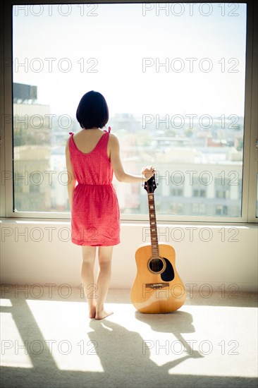 Asian woman holding guitar in window