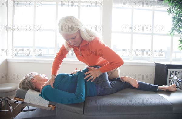 Caucasian chiropractor stretching back of client