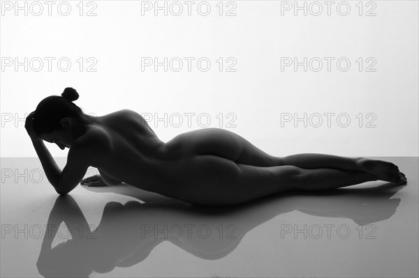 Rear view of nude woman laying on reflective surface