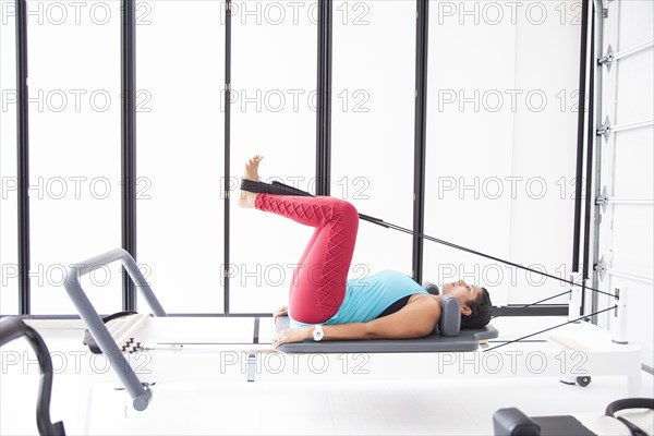 Asian woman using exercise machine in gymnasium