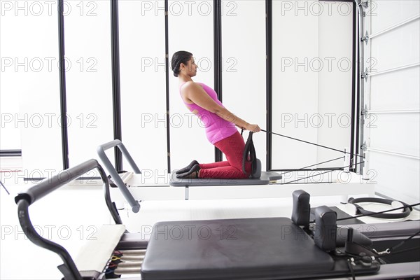 Asian woman using exercise machine in gymnasium