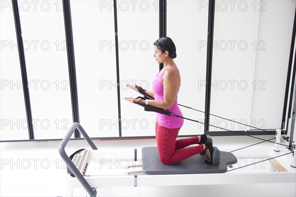 Asian woman using exercise machine in gymnasium