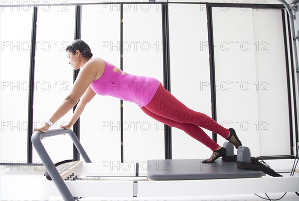 Asian woman using exercise machine in gymnasium