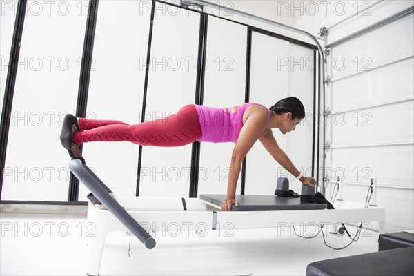 Asian woman using exercise machine in gymnasium