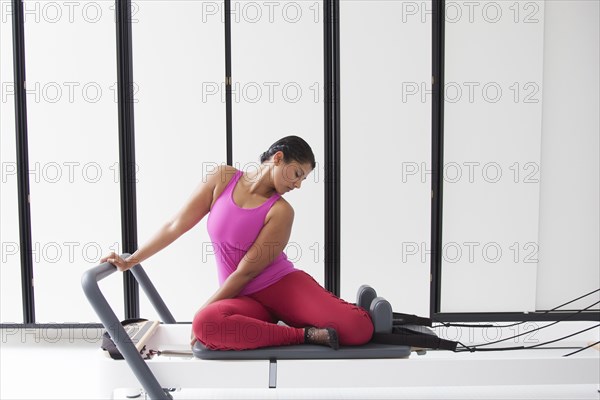 Asian woman using exercise machine in gymnasium