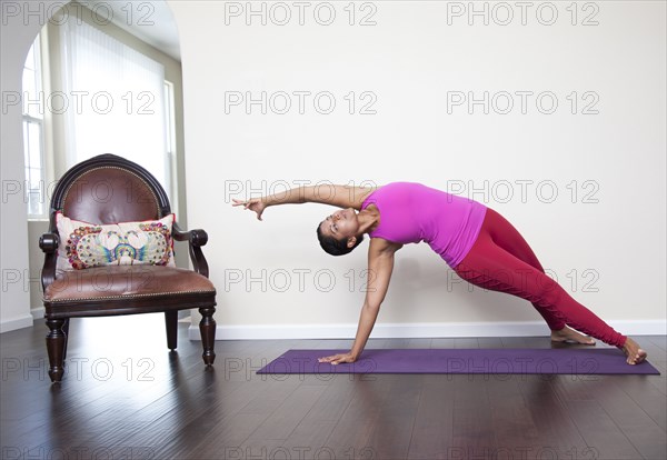 Asian woman practicing yoga in living room